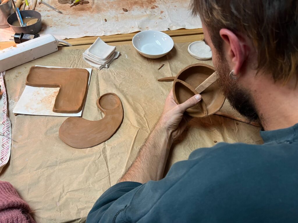 Jovem moldando o barro num workshop da secção de artesanato